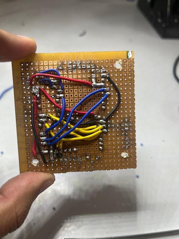 CanSat PCB underside showing hand-soldered through-hole connections with red, black, blue, and yellow wire routing